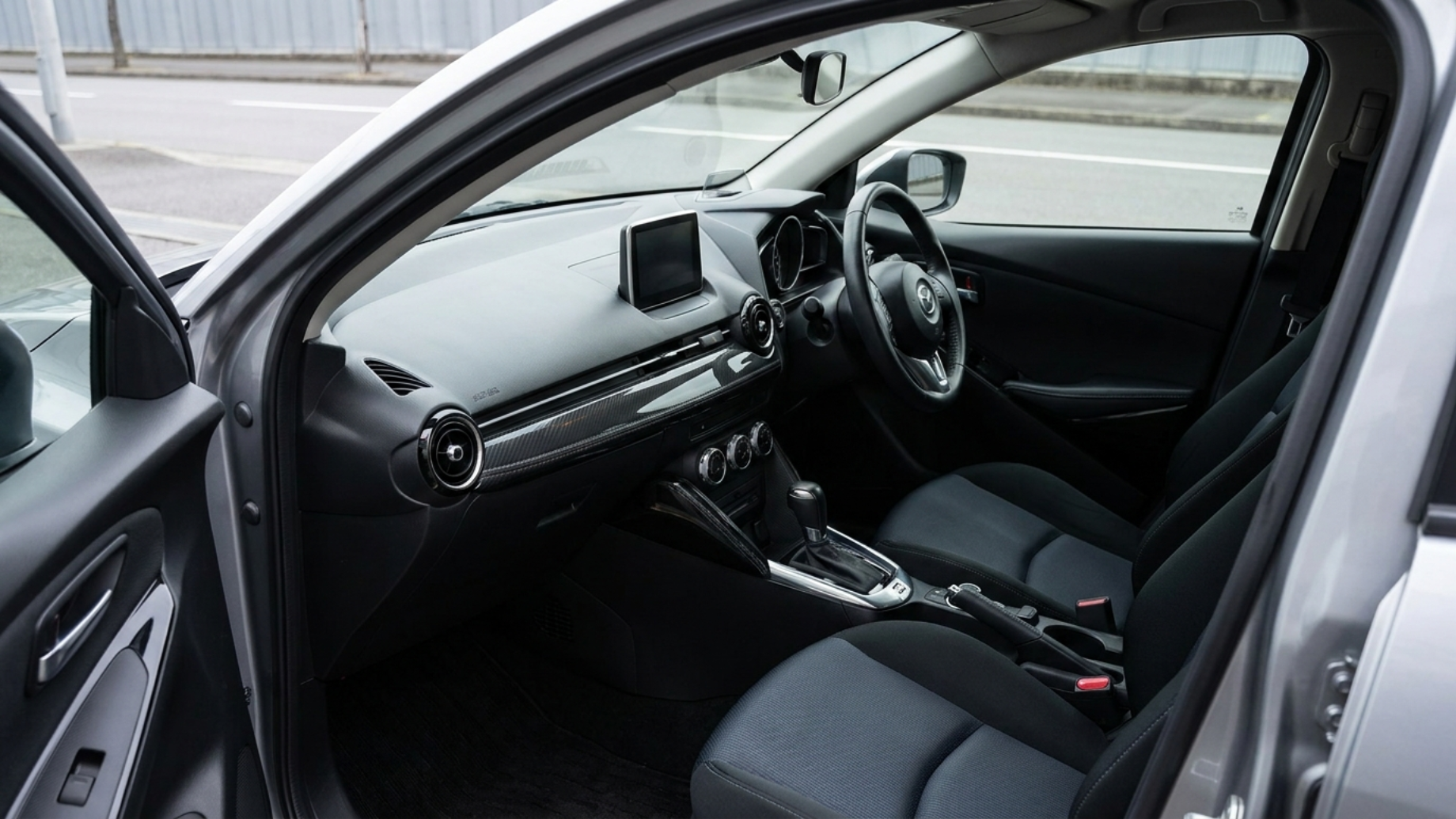 Салон Mazda Demio DJ общим планом: лакированные панели, кожа на селекторе, дневной свет