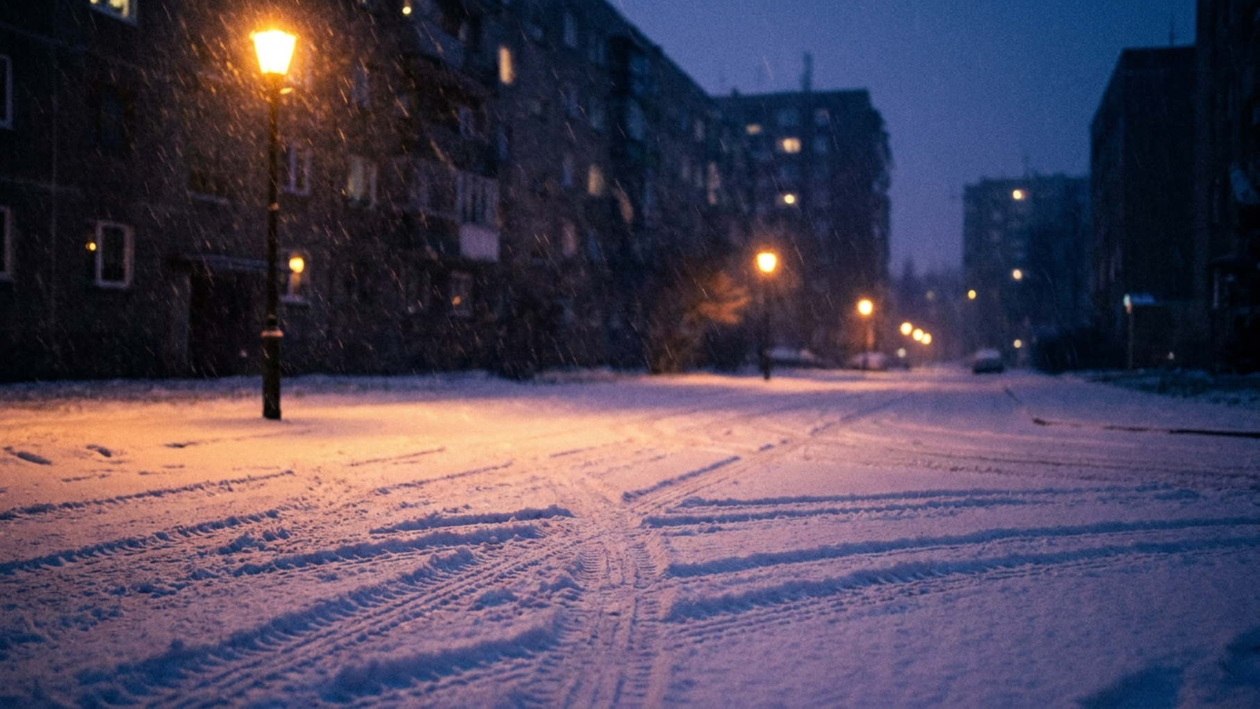 Заснеженная городская дорога в сумерках, следы шин на снегу