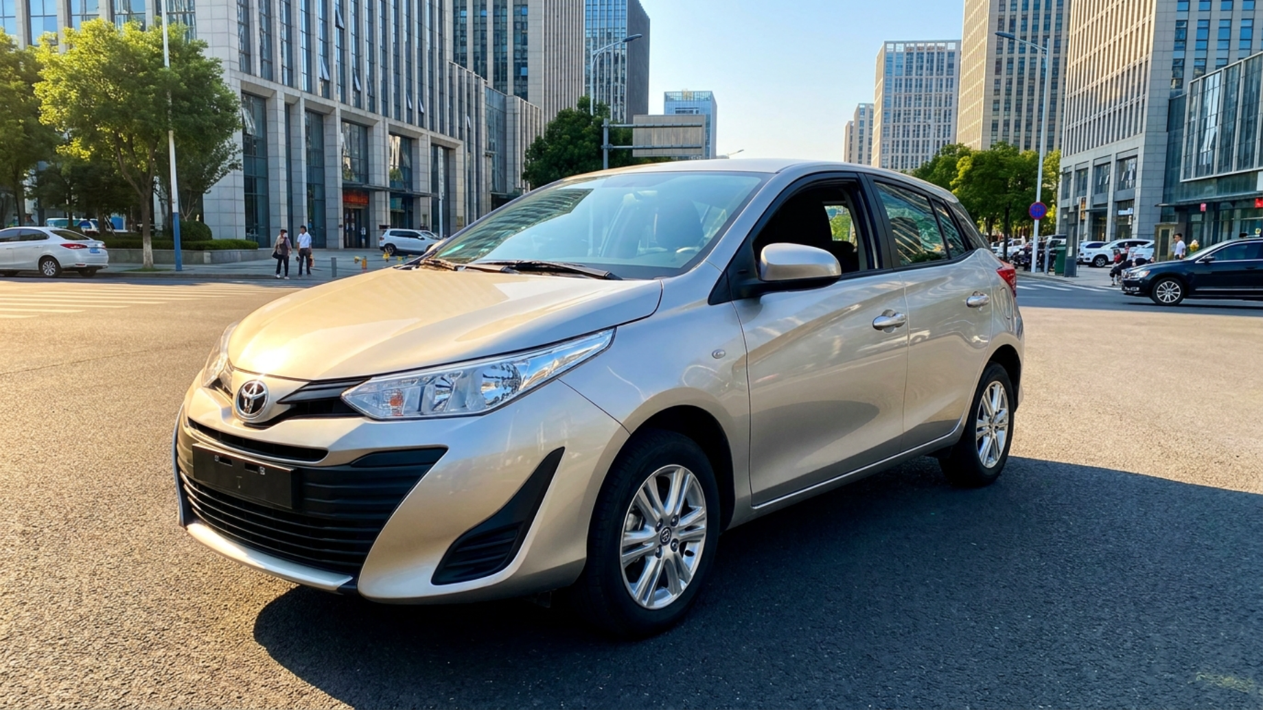 Toyota Yaris L из Китая, левый руль, вид спереди 3/4 на городской улице